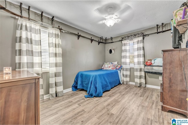 bedroom with ceiling fan, a textured ceiling, and light hardwood / wood-style flooring