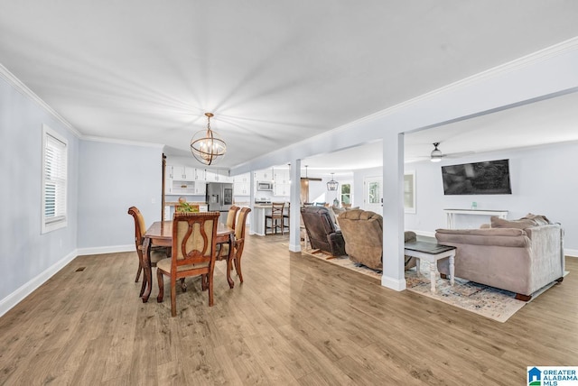 dining room featuring ornamental molding, light hardwood / wood-style floors, ceiling fan with notable chandelier, and plenty of natural light