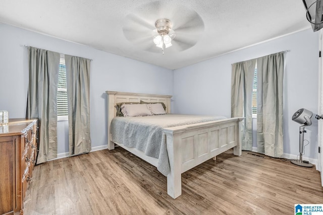 bedroom featuring ceiling fan, light wood-type flooring, and a textured ceiling