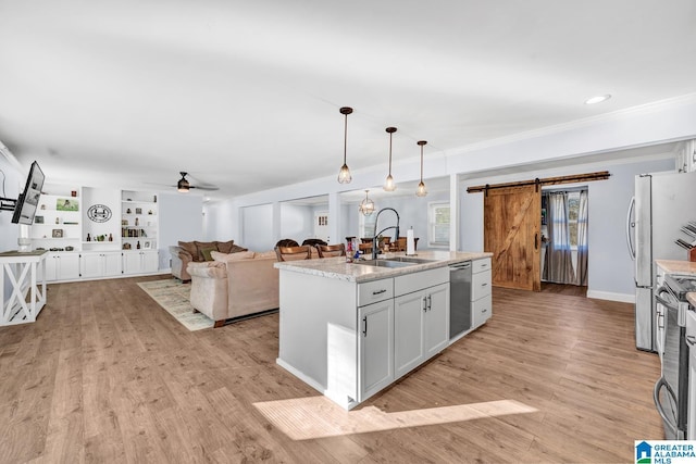 kitchen featuring a barn door, pendant lighting, sink, an island with sink, and built in shelves