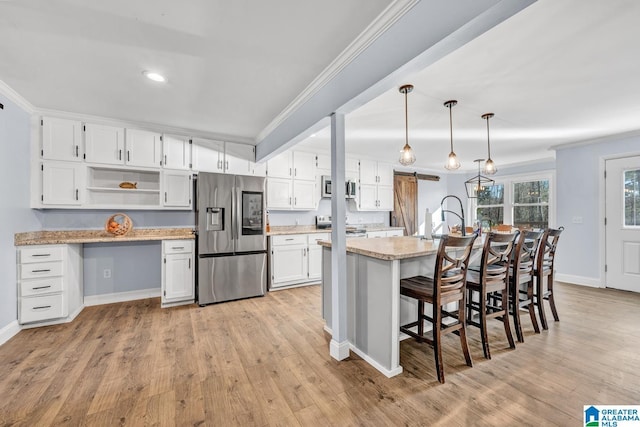 kitchen featuring appliances with stainless steel finishes, light wood-type flooring, hanging light fixtures, white cabinets, and a breakfast bar