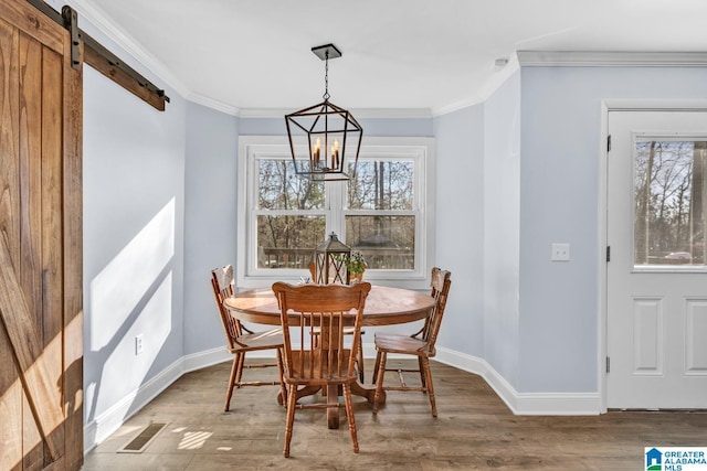 dining area with a chandelier, crown molding, a barn door, and hardwood / wood-style flooring