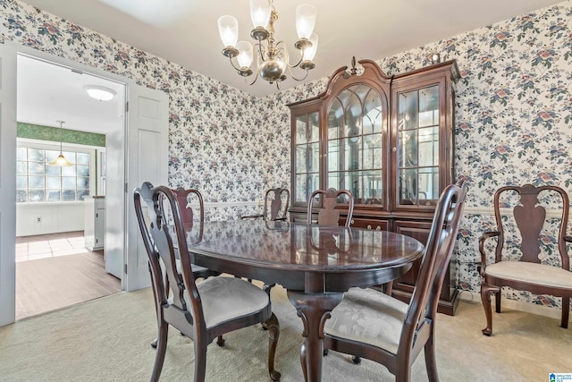 carpeted dining area with a chandelier