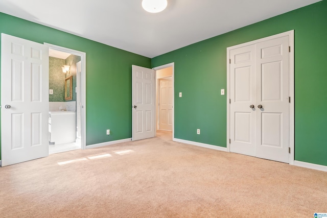 unfurnished bedroom with light carpet and connected bathroom