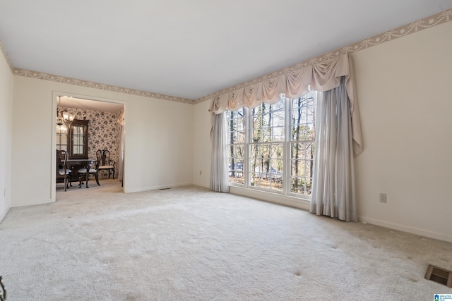 unfurnished room with an inviting chandelier and carpet flooring