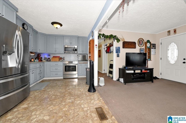 kitchen with backsplash, appliances with stainless steel finishes, gray cabinets, and a textured ceiling