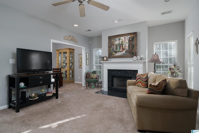 carpeted living room featuring ceiling fan and a premium fireplace