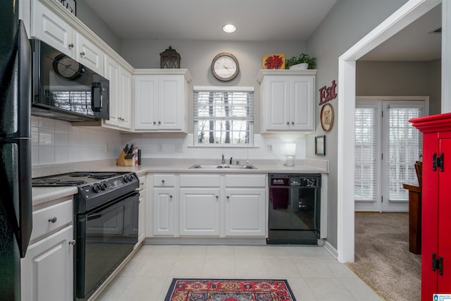 kitchen featuring sink, black appliances, white cabinetry, and light carpet