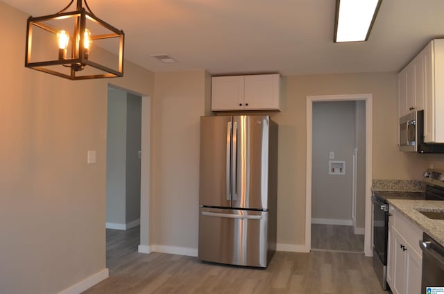 kitchen with light stone counters, decorative light fixtures, light hardwood / wood-style flooring, stainless steel appliances, and white cabinets