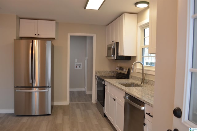 kitchen with white cabinetry, appliances with stainless steel finishes, light stone countertops, and sink