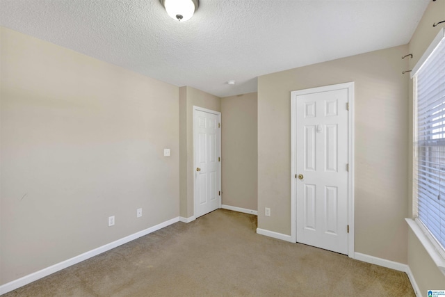 unfurnished bedroom with a textured ceiling and light colored carpet