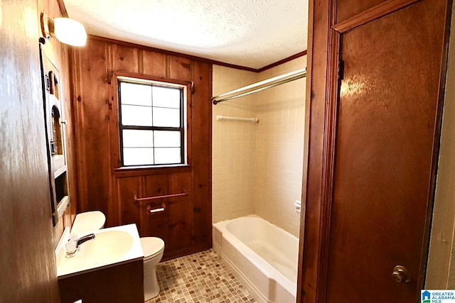 full bathroom with toilet, a textured ceiling, wooden walls, and vanity