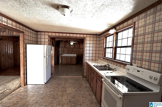 kitchen featuring sink, white appliances, and a textured ceiling