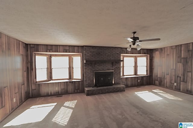 unfurnished living room featuring ceiling fan, a textured ceiling, and a fireplace