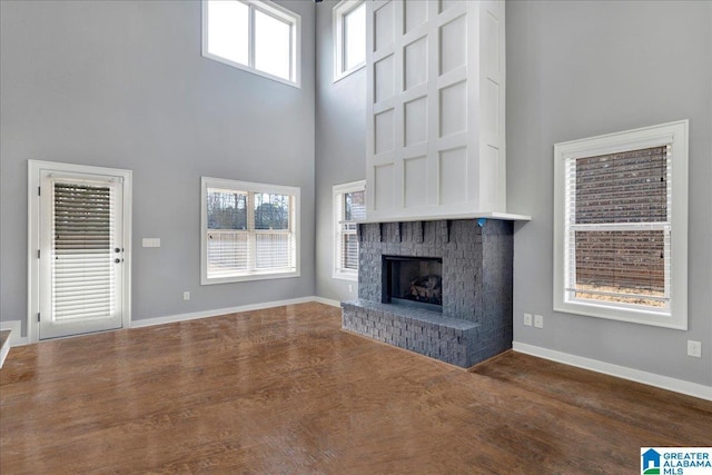 unfurnished living room featuring dark wood-type flooring, a fireplace, and a high ceiling