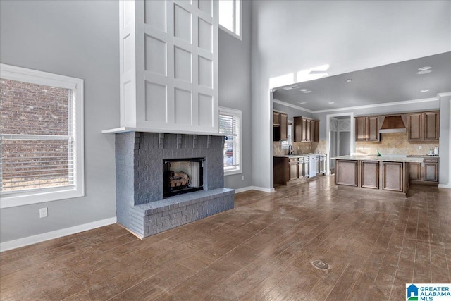 unfurnished living room featuring a brick fireplace, dark hardwood / wood-style floors, and a healthy amount of sunlight