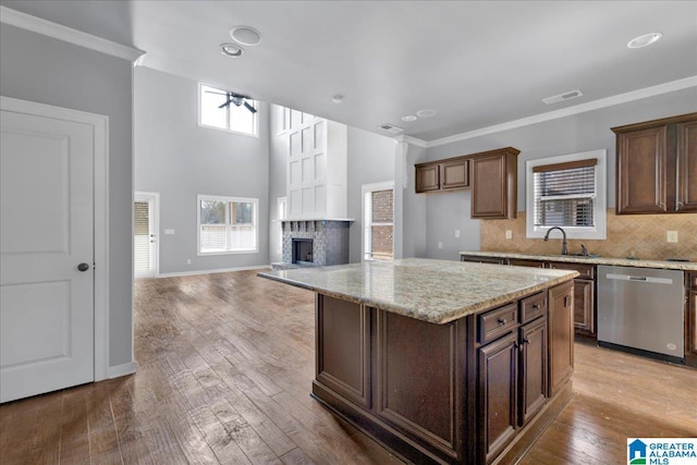 kitchen with dishwasher, sink, a center island, light stone countertops, and light hardwood / wood-style flooring