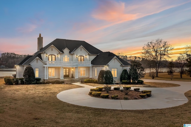 french country inspired facade featuring a lawn and a balcony