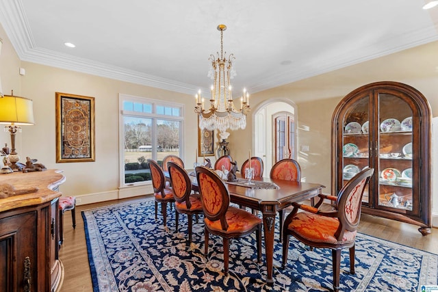 dining space with light wood-type flooring, crown molding, and a chandelier