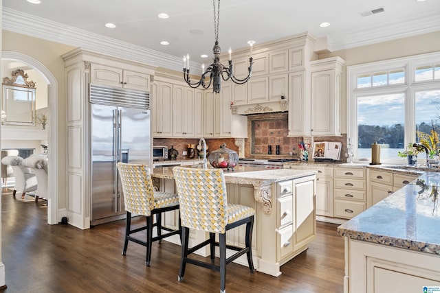 kitchen with pendant lighting, appliances with stainless steel finishes, a center island, and cream cabinets