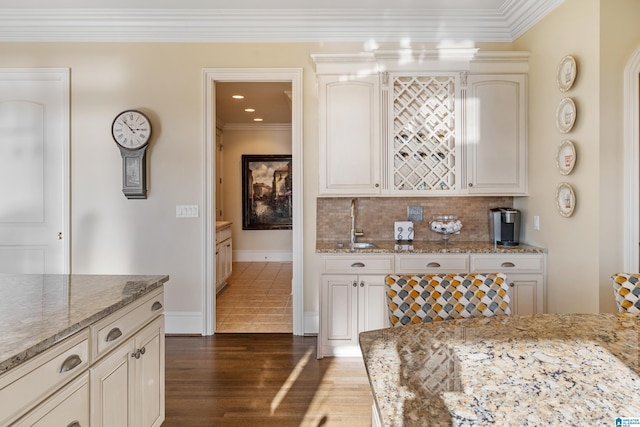 kitchen featuring sink, backsplash, dark hardwood / wood-style floors, ornamental molding, and light stone counters