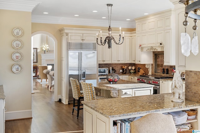 kitchen featuring cream cabinetry, light stone counters, high quality appliances, and a breakfast bar area