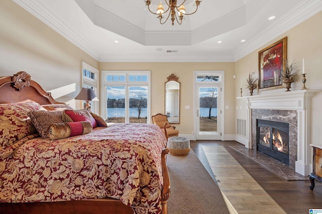 bedroom with dark hardwood / wood-style floors, a fireplace, access to outside, a raised ceiling, and an inviting chandelier