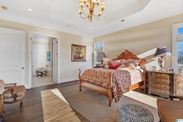 bedroom with crown molding, hardwood / wood-style flooring, a tray ceiling, and a notable chandelier