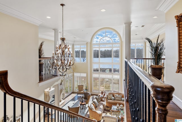 interior space with hardwood / wood-style floors, ornamental molding, a water view, a chandelier, and ornate columns