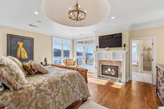 bedroom with ensuite bathroom, access to outside, a fireplace, wood-type flooring, and a chandelier