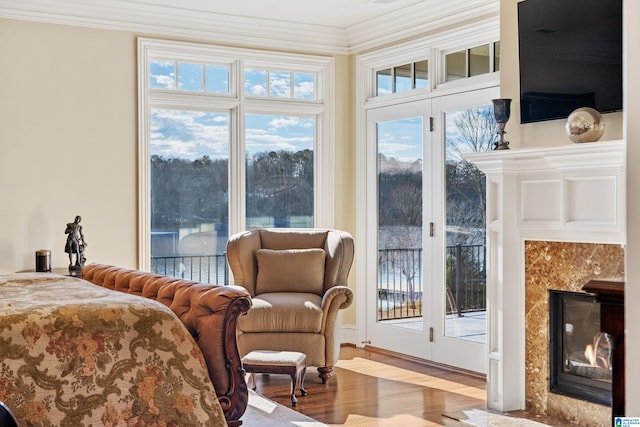 bedroom with crown molding, light hardwood / wood-style flooring, access to outside, and a premium fireplace