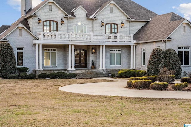 french country home featuring a front lawn, french doors, and a balcony