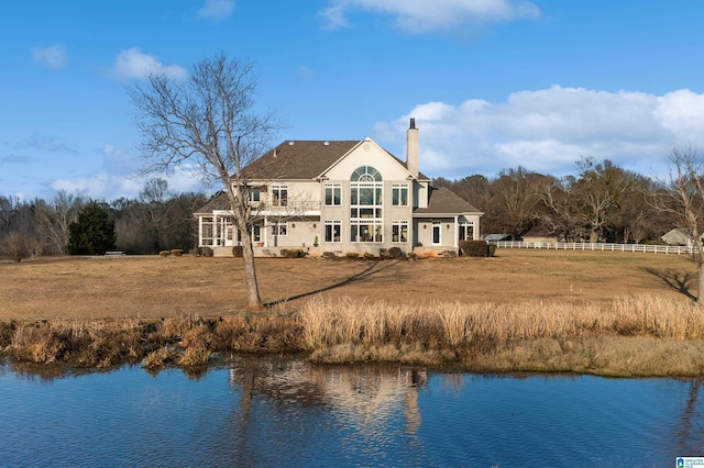 rear view of house featuring a water view and a yard