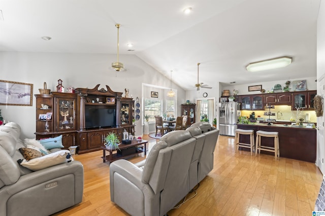 living room with lofted ceiling, light wood-type flooring, and ceiling fan