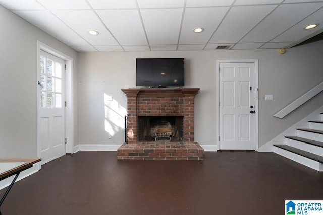 unfurnished living room with a drop ceiling and a fireplace