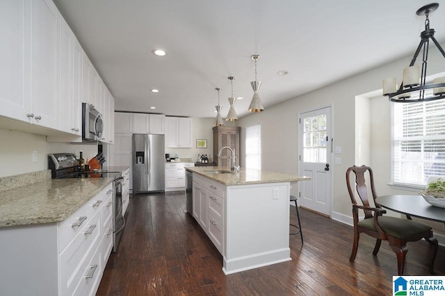 kitchen with hanging light fixtures, sink, white cabinets, a kitchen island with sink, and stainless steel appliances