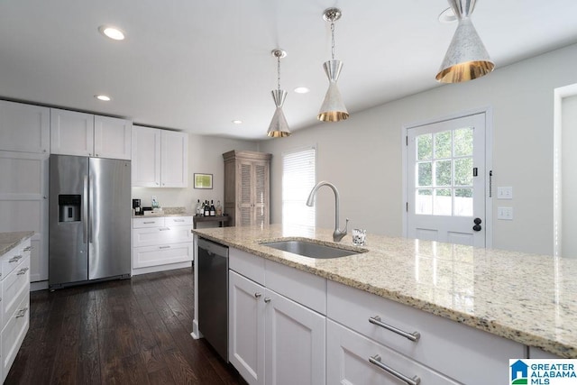 kitchen with appliances with stainless steel finishes, white cabinetry, sink, hanging light fixtures, and light stone counters