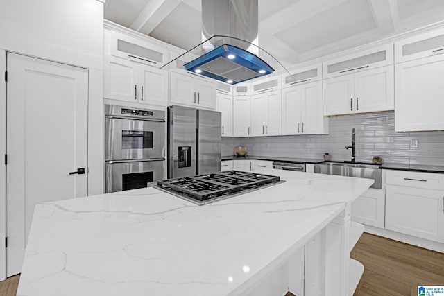 kitchen featuring appliances with stainless steel finishes, white cabinets, and island exhaust hood