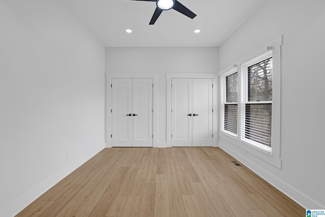 unfurnished bedroom featuring two closets, ceiling fan, and light hardwood / wood-style floors