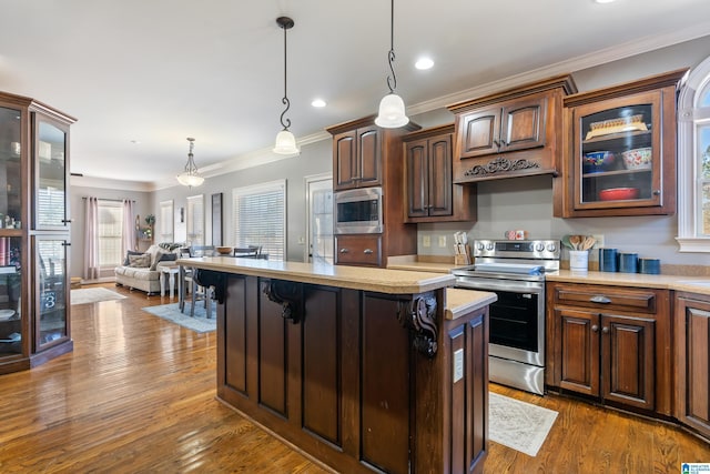 kitchen featuring decorative light fixtures, dark brown cabinetry, ornamental molding, and stainless steel appliances