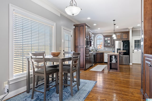 dining space featuring dark hardwood / wood-style flooring, crown molding, and plenty of natural light