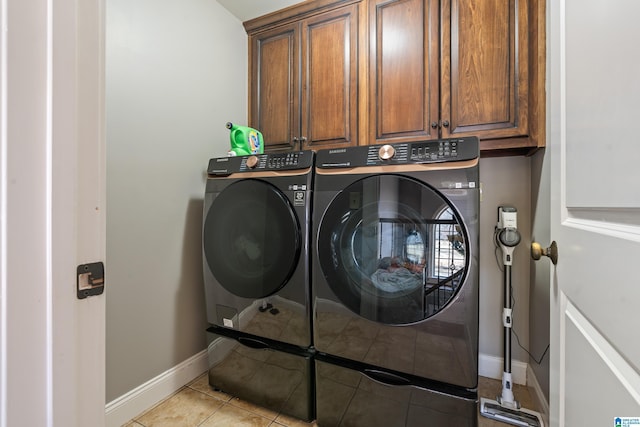 laundry area featuring cabinets, light tile patterned floors, and washing machine and dryer