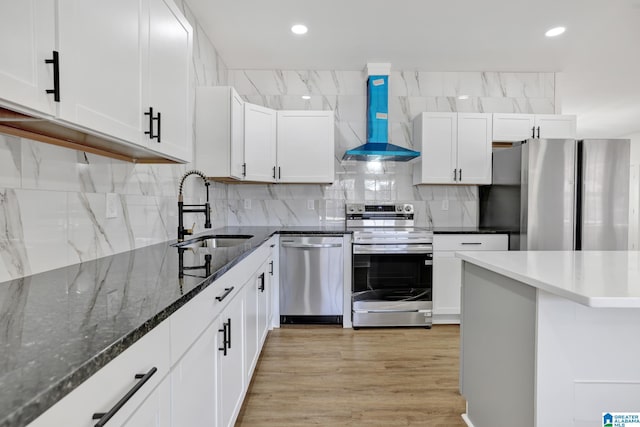 kitchen with white cabinetry, sink, wall chimney range hood, and stainless steel appliances