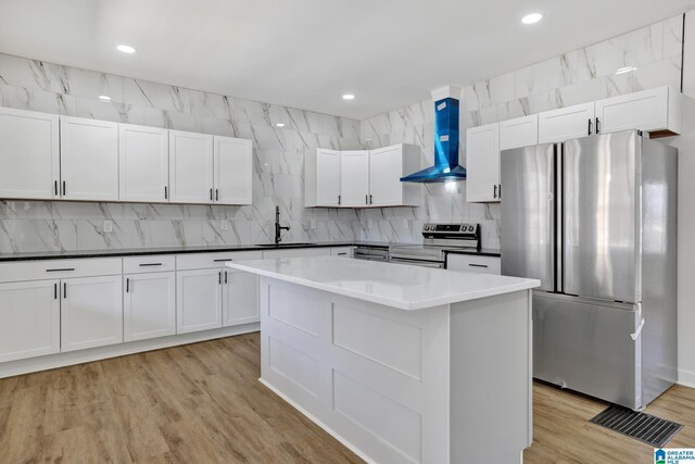 kitchen with appliances with stainless steel finishes, sink, white cabinets, and wall chimney exhaust hood