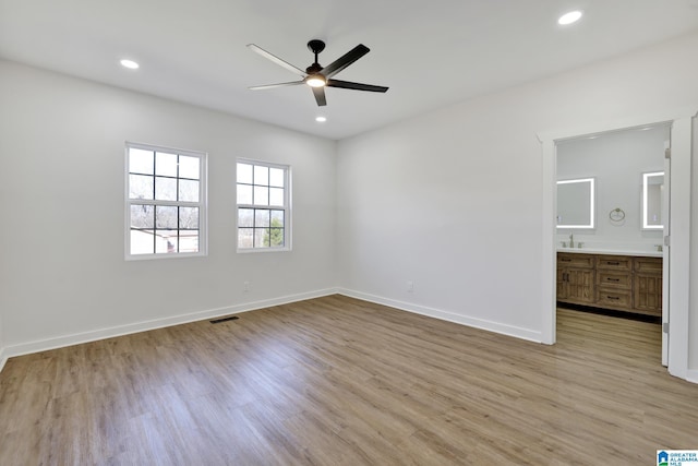 unfurnished bedroom featuring ceiling fan, connected bathroom, sink, and light hardwood / wood-style flooring