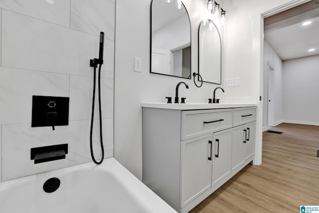 bathroom featuring tiled shower / bath combo, vanity, and wood-type flooring