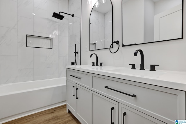 bathroom featuring wood-type flooring, tiled shower / bath combo, and vanity