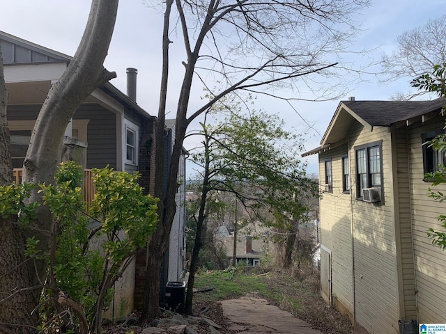 view of side of property featuring a shingled roof and cooling unit