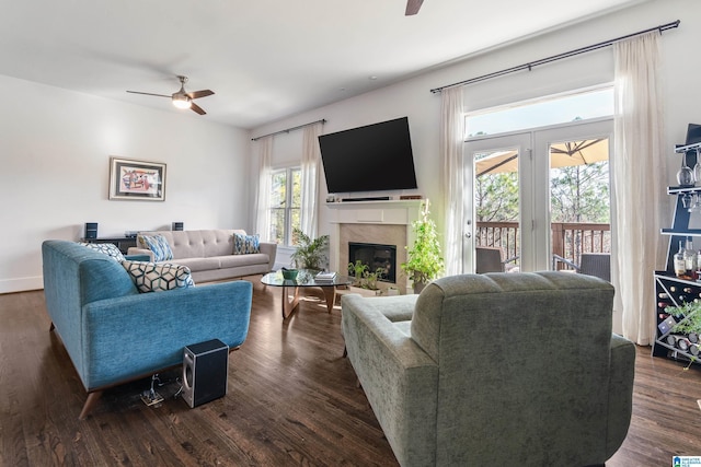 living room with ceiling fan, a high end fireplace, dark hardwood / wood-style flooring, and a healthy amount of sunlight