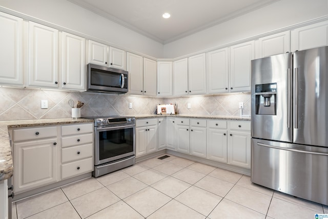 kitchen with white cabinets, appliances with stainless steel finishes, light tile patterned flooring, and crown molding